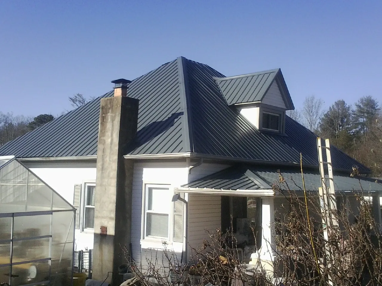 Dark blue standing seam metal roof on a white farmhouse with dormer — Slate & Tile Roof Repair by Roofing Brothers in Adel