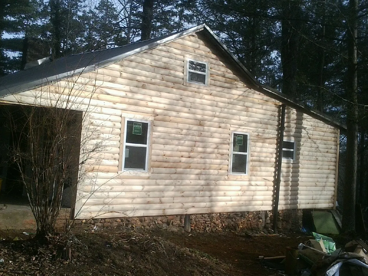 New log siding and dark metal roofing on a gable end in Adel