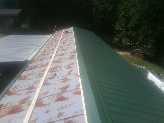 Old rusted panels beside newly installed green metal roofing — Wind Damage Roof Repair by Roofing Brothers in Adel