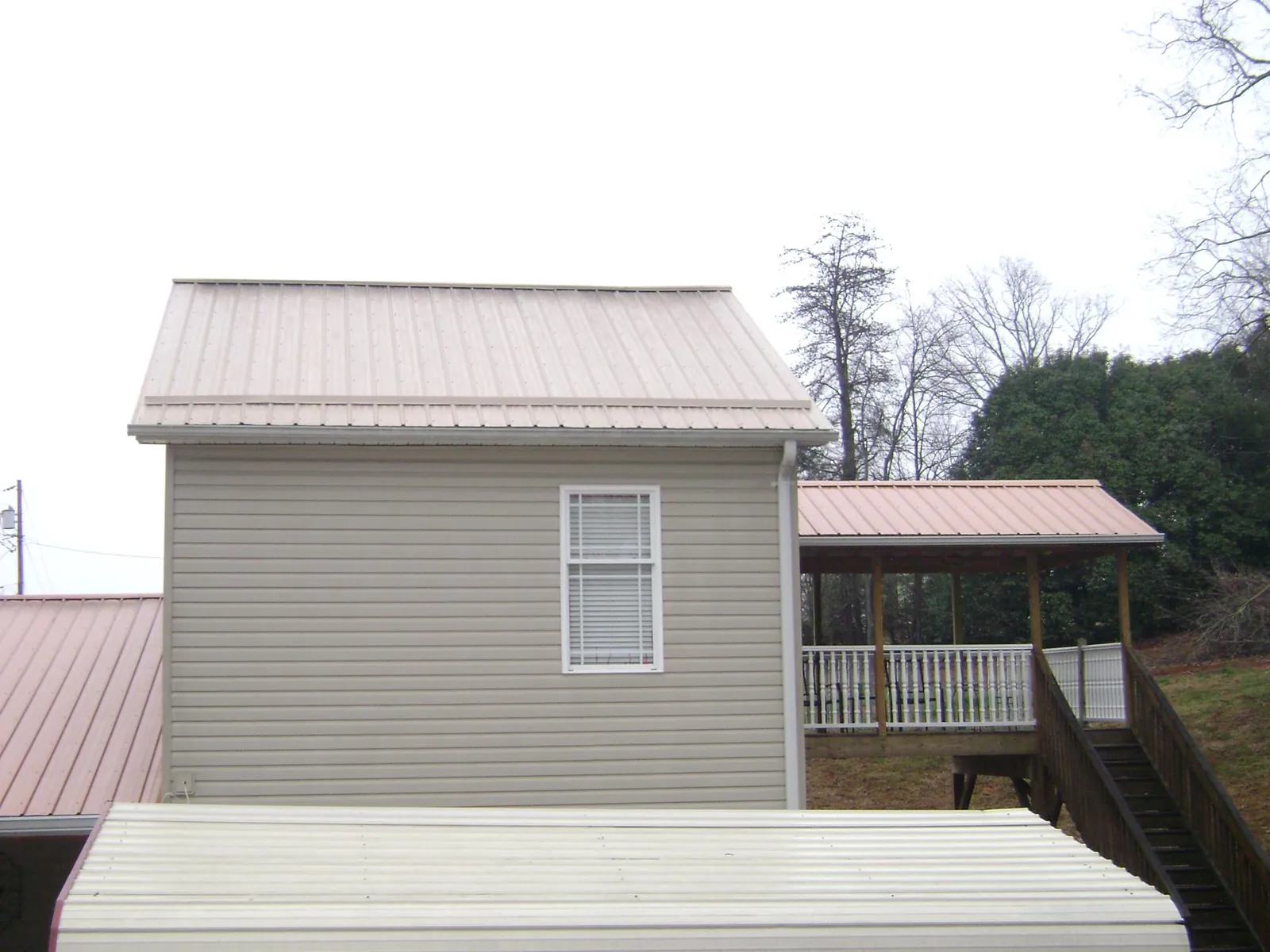 Tan metal roofs on a two story addition and attached porch, from a Roof Replacement job in Adel