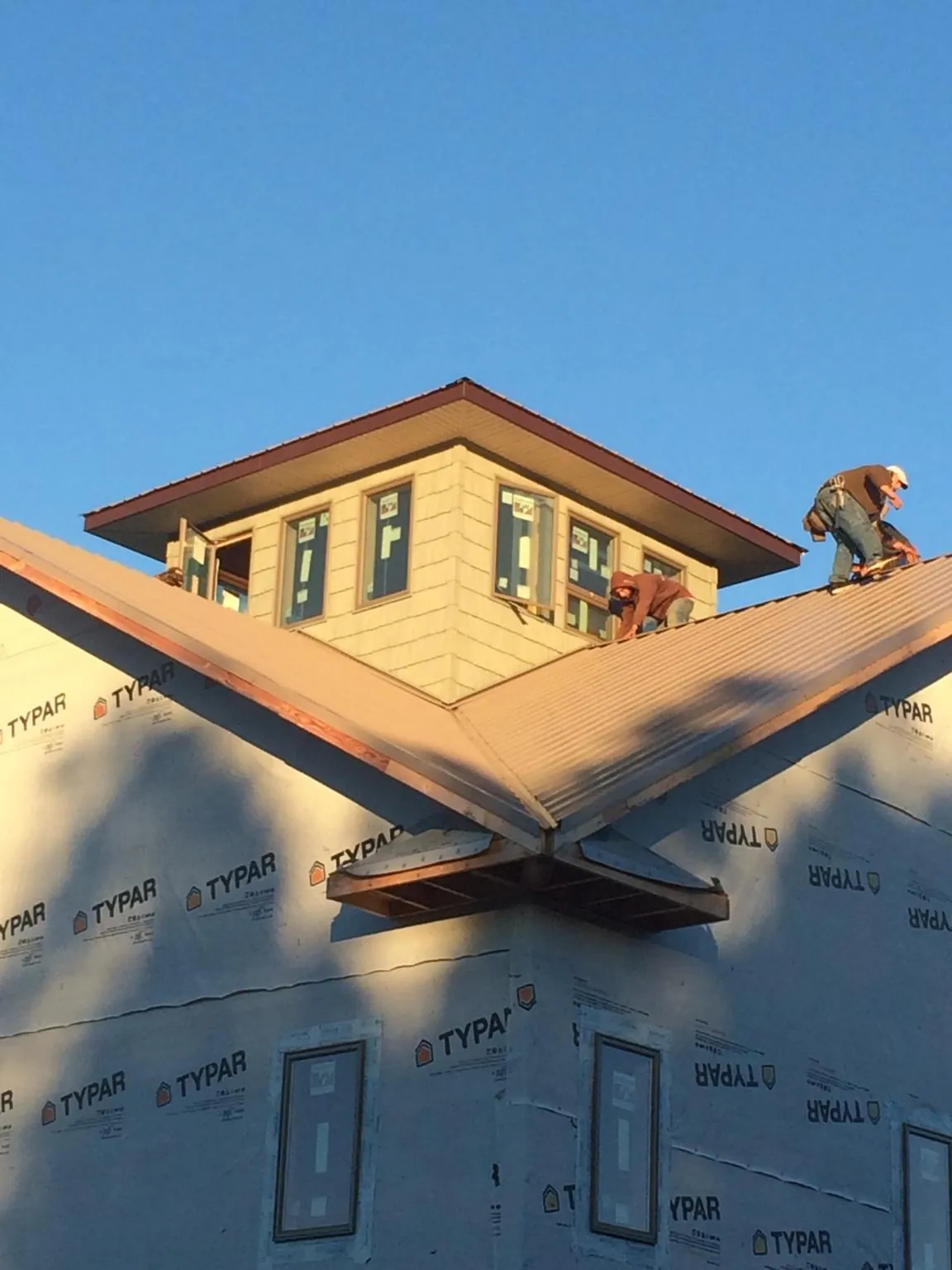 Roofers working around a rooftop cupola on a new metal roof at sunset — Roof Waterproofing in Adel by Roofing Brothers
